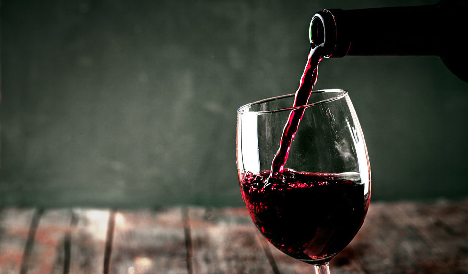 Calice di vino rosso versato da bottiglia